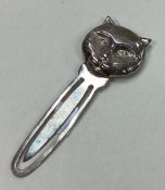 A silver bookmark in the form of a cat bearing import marks.