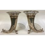 A pair of pierced silver vases in the form of dolphins.