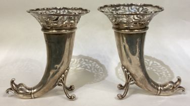 A pair of pierced silver vases in the form of dolphins.