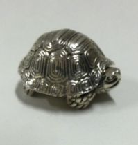 A heavy silver pill box with hinged lid in the form of a tortoise.