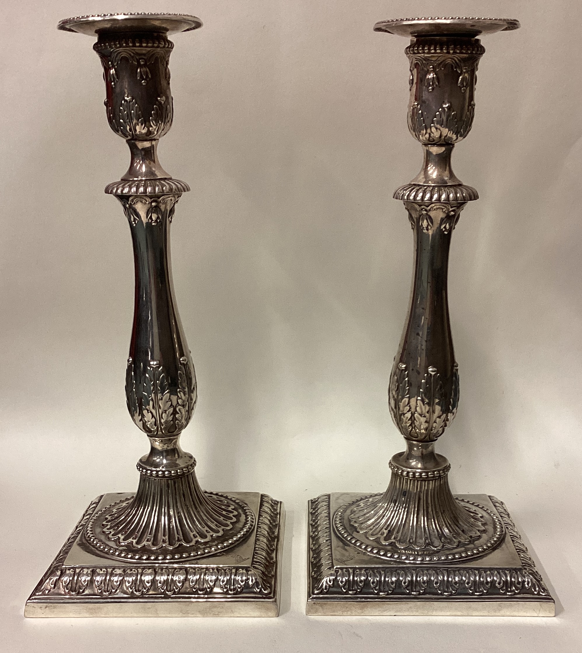 A pair of 18th Century Georgian cast silver candlesticks on square bases.