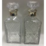 A pair of large glass decanters with silver collars.