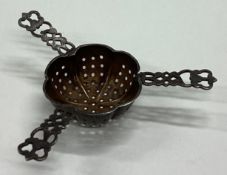 A heavy silver tea strainer with pierced decoration.