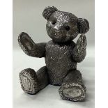 A novelty silver figure of a clapping teddy bear.