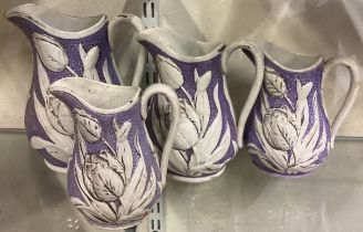 A group of four graduating Staffordshire lustreware lilac ceramic jugs with tulip pattern.
