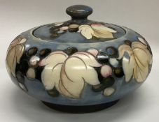WILLIAM MOORCROFT: A squat powder jar and cover decorated with leaves and berries.