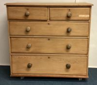 A stripped pine chest of five drawers.