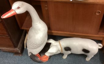 A plaster figure of a goose and a pig.