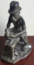 A stone figure of a seated cobbler with hat.