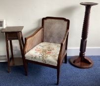 A small cane back chair together with a table and a plant pedestal.