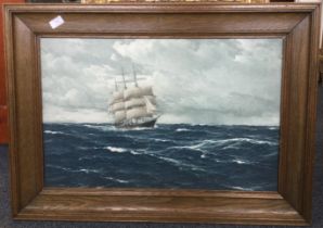 A wood framed and glazed picture of a galleon at sea.