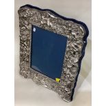 A large modern silver picture frame chased with flowers.