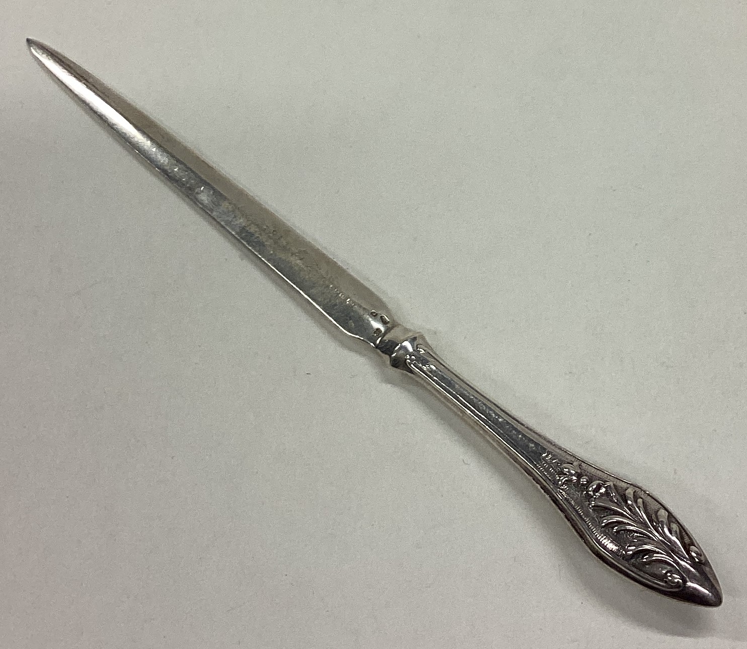 A silver letter opener bearing import marks.