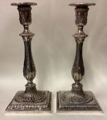 A pair of 18th Century Georgian cast silver candlesticks on square bases.