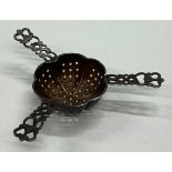 A heavy silver tea strainer with pierced decoration.