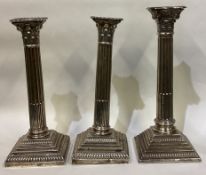 A heavy pair of silver Corinthian column candlesticks of typical form together with one other.