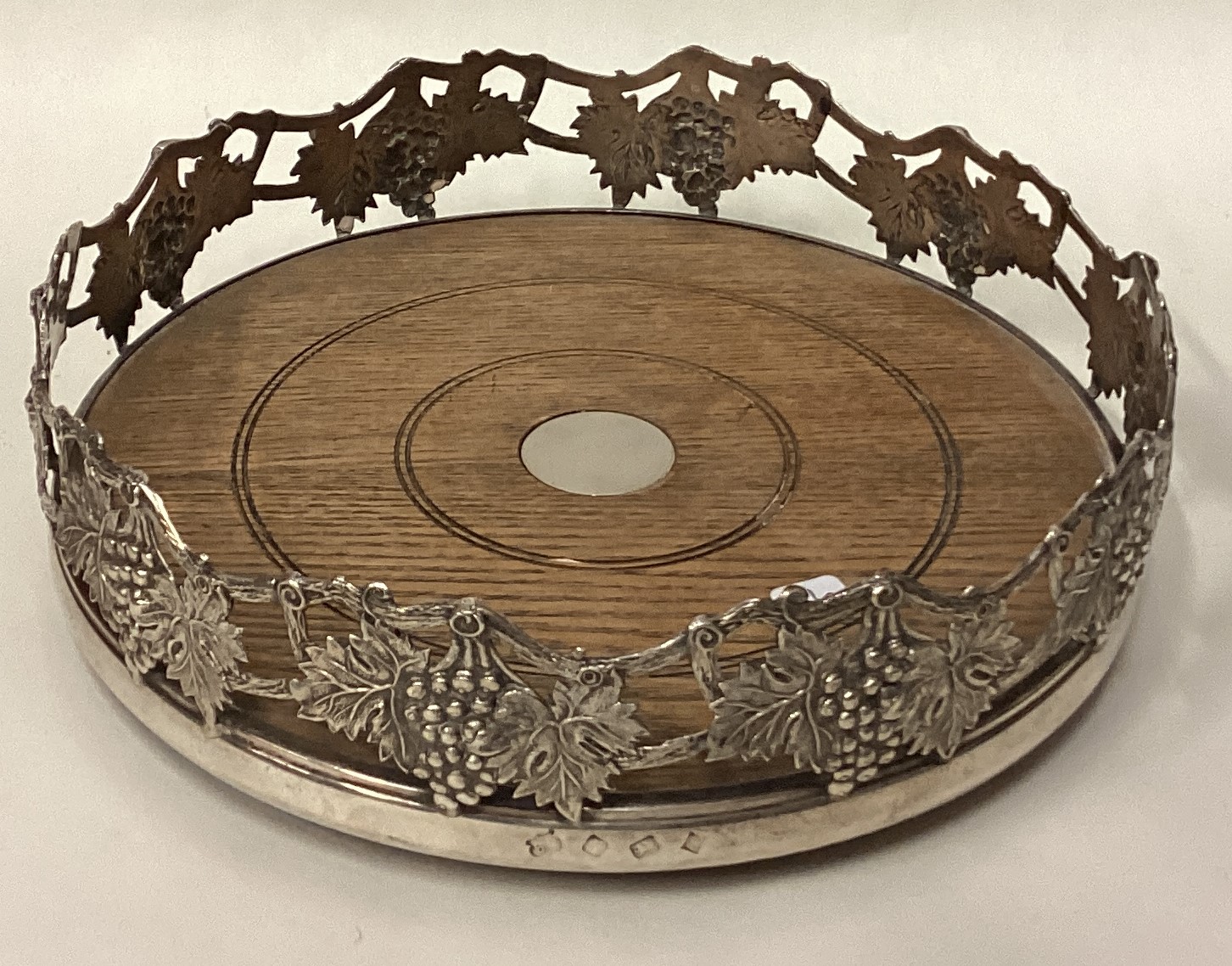 A large silver magnum coaster pierced with grapevine decoration.