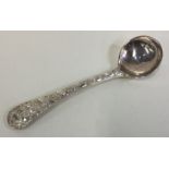 A silver mustard spoon embossed with figural and foliage decoration.