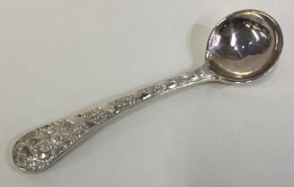 A silver mustard spoon embossed with figural and foliage decoration.