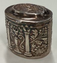 A silver pill box with hinged lid decorated with basket of flowers.