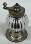 A silver plated and glass pepper grinder.