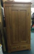 A stripped pine single door wardrobe.