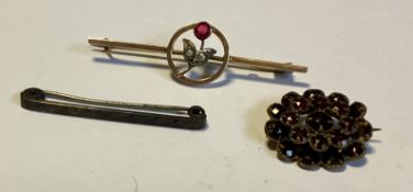 A small gold brooch together with two silver examples.