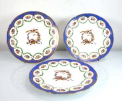 A set of three 19th century cabinet plates, each decorated with a foliate wreath and a bird and cage