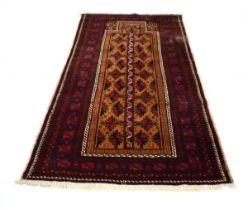 A Persian Balouch rug with a golden and red ground, 230 x 115 cm Some heavy wear in places. Some