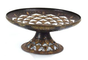 A metalwares tazza inlaid with yellow metal depicting a stylised Adam & Eve scene in the Garden of