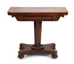 A mid-19th century mahogany games table, the folding surface over a scrolled frieze, on tapering