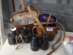 Two pairs of binoculars, possibly military issue, both with leather cases