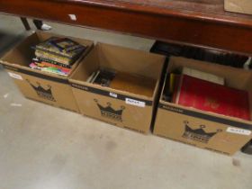 Three boxes containing children's annuals, children's and others novels, plus reference books