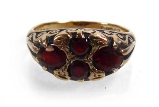 A 9ct yellow gold ring set four oval garnets in a scrolled setting, London 1973, ring size P, 5.4