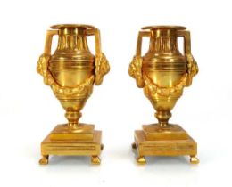 A pair of Regency gilt bronze candlesticks with lion masks handles and swags, h. 13 cm