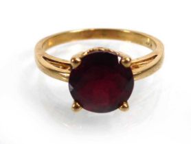 A 14ct yellow gold ring set round cut red stone in a raised four claw setting, ring size N 1/2, 3
