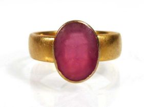 A 22ct yellow gold ring set oval pink glass in a rubover setting, Birmingham 1938, ring size O, 6.
