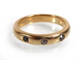 A yellow metal band ring set one diamond and two paste stones in recessed settings, ring size 5.8