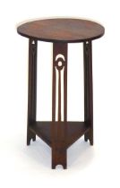 An Arts & Crafts oak side table, the circular top on fretwork supports joined by a second tier,