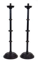 A pair of ebonised Ecclesiastical floor-standing candlesticks with undulating bodies, h. 132 cm *