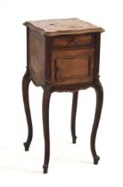 A French walnut bedside table, the rouge marble surface over a door and drawer, with marble lined