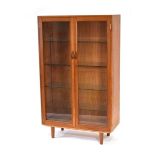 A 1960's teak cabinet, the pair of glazed doors enclosing glass shelves, on later turned legs, 90