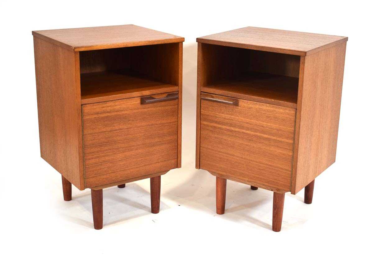 A pair of 1970's teak bedside cabinet, each with a single door, moulded handle and later tapering