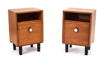 A pair of 1970's teak single door bedside cabinets with circular handles and stainless decoration,