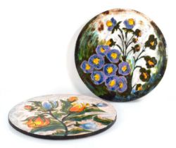 A large pair of 1960's German ceramic wall plaques of circular form decorated with bright flowers,