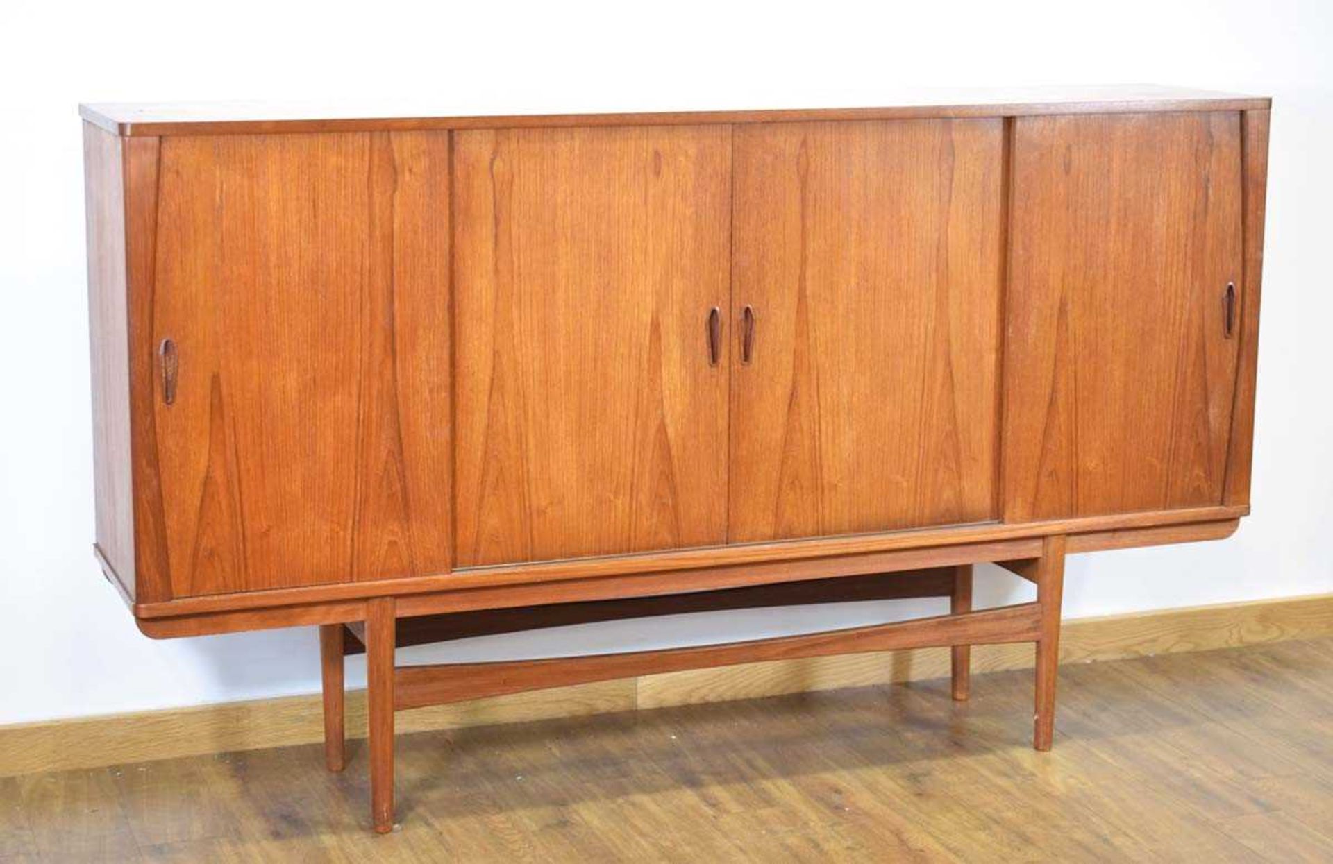 A 1960's Danish teak sideboard cabinet, the four sliding doors enclosing an arrangement of