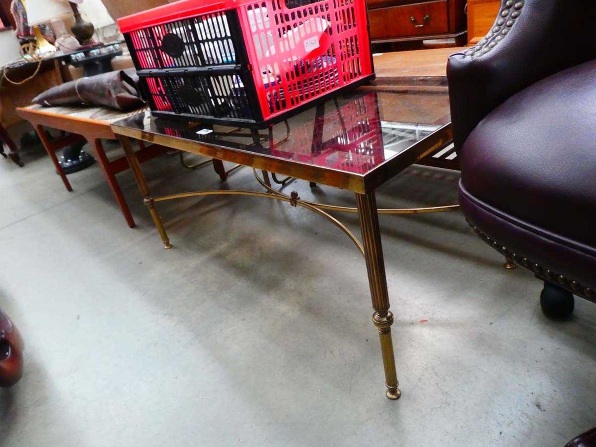 A 1980's brass finished coffee table with a rectangular smoked glass surface and reeded legs in