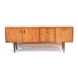 A 1960's G-Plan teak sideboard with a pair of doors, four drawers and a fall-front door, on tapering