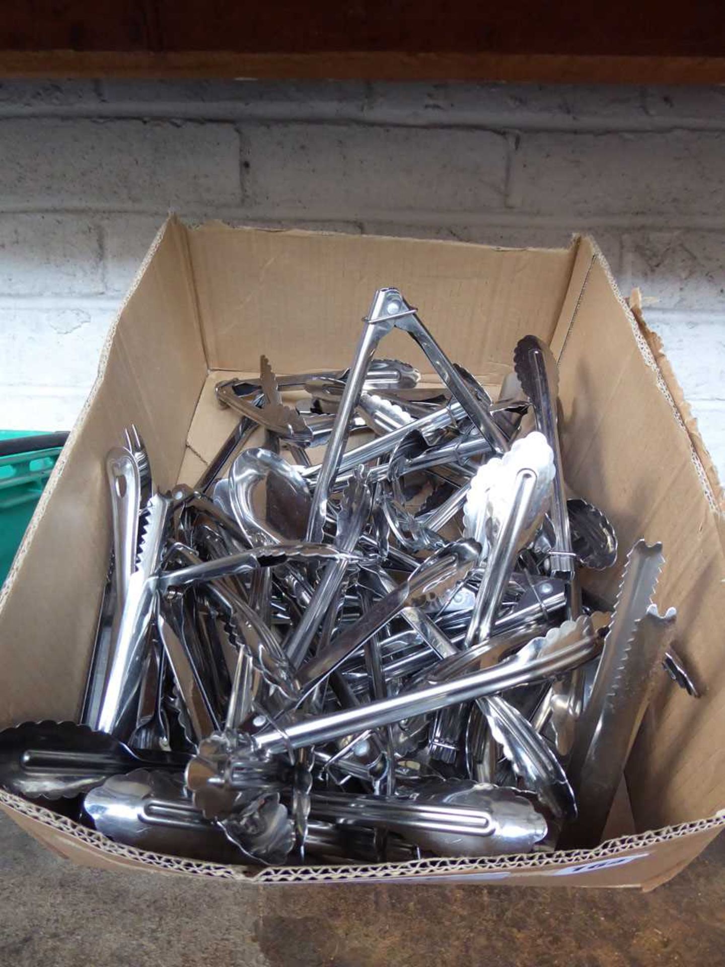Box containing mostly stainless steel serving tongs