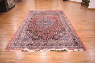 A 20th century Iranian carpet with a central medallion, red ground and matching bands, 330 x 198 cm